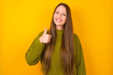 Genç bir kadın elleriyle mutlu bir jest yapıyor. Kameraya bakıp başarıyı gösteren ifade onaylanıyor.