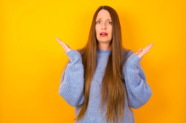 Öfkeli genç kadın şaşkınlıkla el kol hareketi yapar, tatminsizlikle kaşlarını çatar..