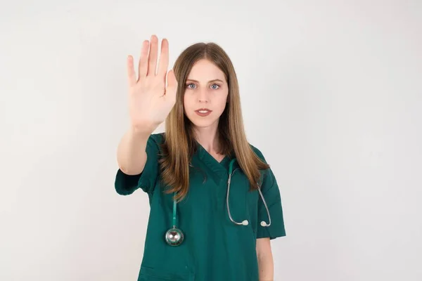 白人の背景に停止標識を示す若い白人医師の女性 — ストック写真