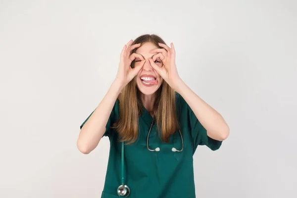 Młoda Piękna Pielęgniarka Robi Gest Jak Lornetka Wystająca Języka Oczy — Zdjęcie stockowe