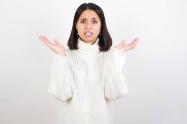 Öfkeli genç kadın şaşkınlıkla el kol hareketi yapar, tatminsizlikle kaşlarını çatar..