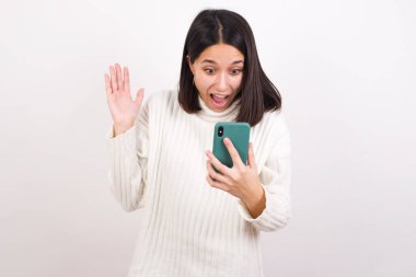 Hücrede el ele tutuşan genç bir kadın haberleri okuyor.