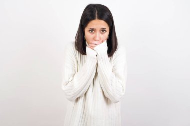 Genç esmer kadın kendini dışarıda üşütmüş, üşümemesini umuyor.