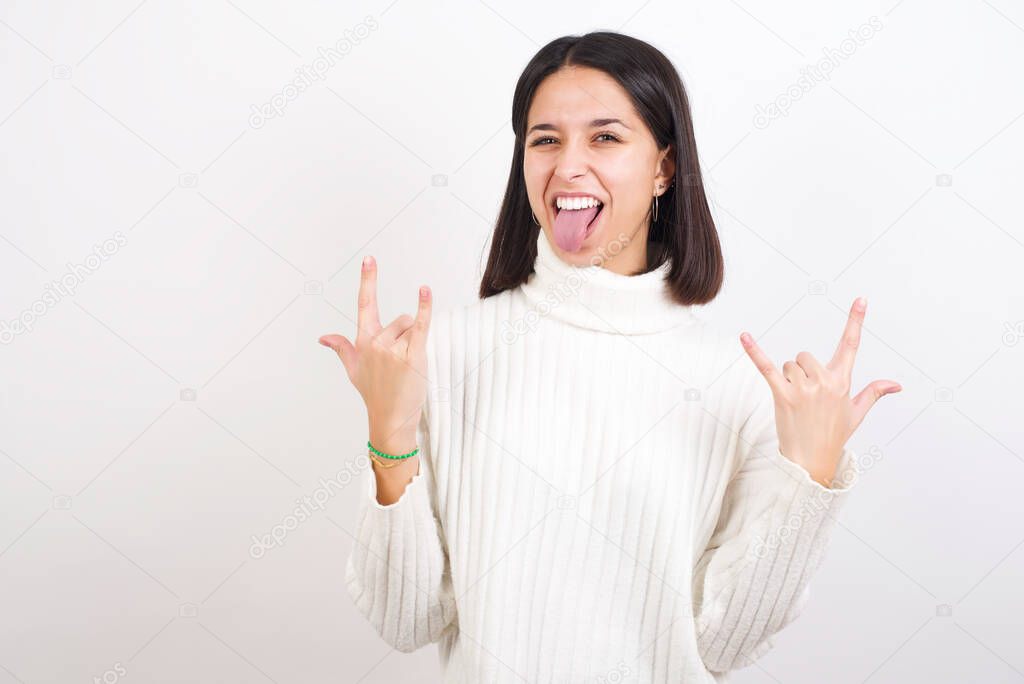 young woman making rock hand gesture and showing tongue