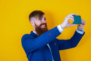 Sarı arka planda cep telefonu olan genç bir adamın portresi.