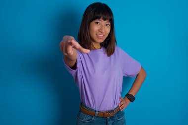 Genç bir kadın kameraya tatmin olmuş, kendinden emin, dostane bir gülümsemeyle bakıyor ve seni seçiyor.