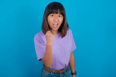 Öfkeyle bağırırken sinirli ve öfkeli genç bir kadın yumruk kaldırıyor. Öfke ve agresif kavram.