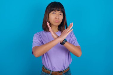 Reddedilmiş genç bir kadın kollarını kavuşturup negatif işaret veriyor, kızgın bir yüz ifadesi.