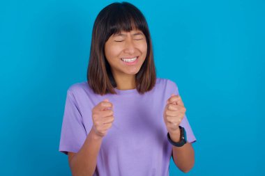 Genç bir kadın zafer kutlamalarında kollarını kaldırarak ve gözlerini kapatarak başarı için heyecanlanıyor. Kazanan konsept.