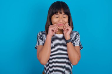 Tatmin olmamış genç bir kadının portresi sırıtıyor, dudaklarını kesiyor ve kameraya rahatsız edici bir şekilde bakıyor, tatsız bir şey duymaktan hoşnutsuzluk duyuyor.