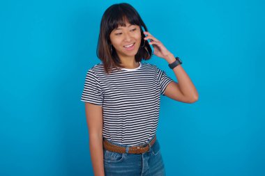 Genç bir kadın bir şey hakkında derin düşünür, modern cep telefonu kullanır, iyi bir mesaj uydurmaya çalışır, işaret parmağını dudaklarının yakınında tutar..