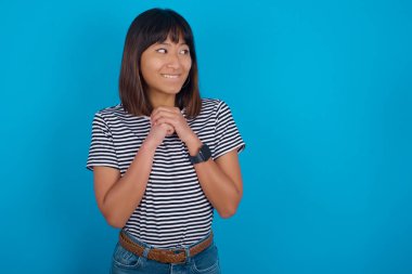 Meraklı genç bir kadın ellerini çenesinin altında tutar dudaklarını ısırır ve ilgilenir..