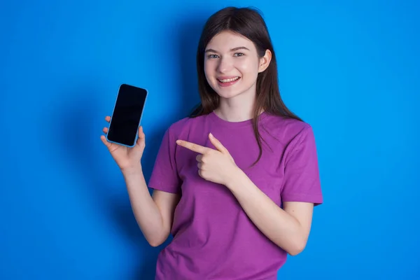 Usmívající Mladá Žena Ukazuje Ukazováčkem Mobilní Telefon Prázdnou Obrazovkou — Stock fotografie