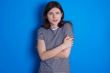 Genç bir kadın kışın soğuktan titriyor ve donuyor. Yüzünde üzgün ve şok ifadesi var..