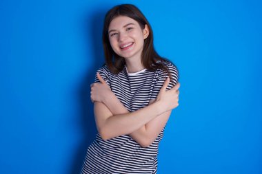 Çekici, memnun, genç bir kadın kendi vücudunu kucaklıyor, rahat pozlar veriyor. Şefkat ve kendine saygı kavramı