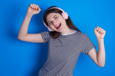 Kaygısız genç kadın kalın sakal ve dişlek gülümseme kaldırır kollarını, dans hareketlerini müziğin ritmiyle kulaklıklarla müzik dinler.