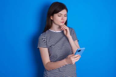 Telefonu elinde tutan düşünceli, mutlu genç bir kadın.