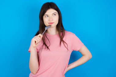 Ağzına kaşık tıkan çok aç, genç esmer kadın lezzetli bir yemek hayal ediyor.