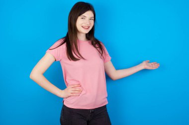 Genç esmer kadın kendini mutlu ve neşeli hissediyor, gülümsüyor ve seni selamlıyor, dostça bir jestle içeri davet ediyor.