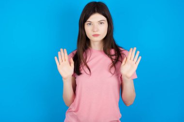 Ciddi genç esmer kadın, avuç içlerini kameraya çeker, jestleri durdurur, duygularını kontrol etmek ve gergin olmamak ister.