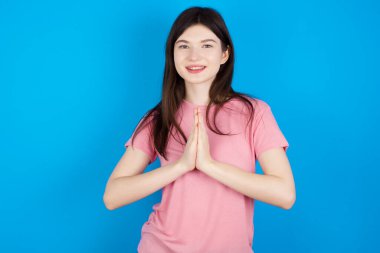 Genç esmer kadın ellerinin birarada dua etmesi af dilemesi kendinden emin bir şekilde gülümsemesi..