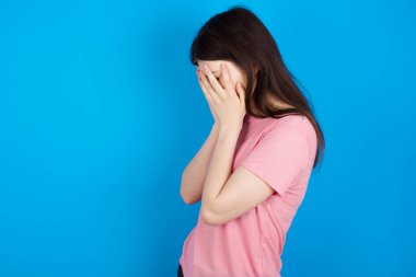 Üzgün genç esmer kadın elleriyle yüzünü kapayarak ağlıyor..