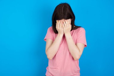 Genç esmer kadın elleriyle yüzünü örtüyor, yıkılmış ve ağlıyor. Üzücü bir kavram