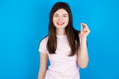 Genç esmer kadın elini göstererek Çin işaret diliyle Q harfinde yedi parmak hareketi gösteriyor. 