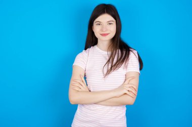 Self confident serious calm young brunette woman stands with arms folded. Shows professional vibe stands in assertive pose.