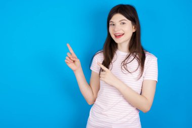 young brunette woman points at copy space indicates for advertising gives right direction