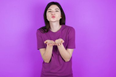 Genç esmer kadın öpücük yolluyor dudaklarıyla ve avuç içleriyle hava öpücüğü yolluyor..