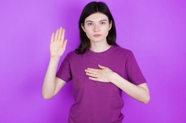 Genç esmer kadın, elleri göğsünde ve avuçları açık yemin ederek sadakat yemini ediyor.