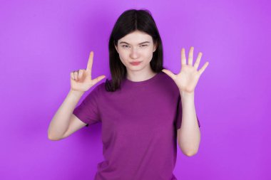 Genç esmer kadın yedi numarayı gösterip işaret ederken kendinden emin ve mutlu gülümsüyor..