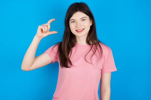 若いブルネットの女性は笑顔で 指を見てカメラで小さなサイズのサインをする手で自信を持ってジェスチャー 概念の測定 — ストック写真