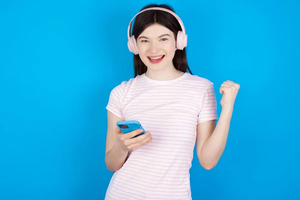 Positieve Jonge Brunette Vrouw Houdt Moderne Mobiele Telefoon Aangesloten Hoofdtelefoon — Stockfoto