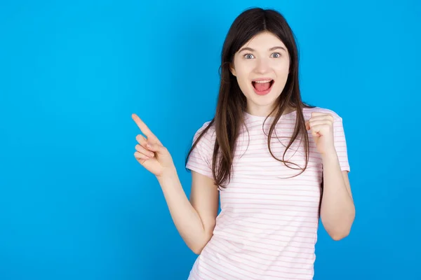 Young Brunette Woman Points Empty Space Holding Fist Winner Gesture — ストック写真