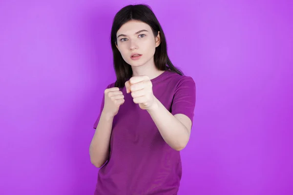 young brunette woman punching fist to fight, aggressive and angry attack, threat and violence