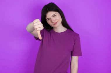 Genç esmer kadın sinirli, sinirli, hayal kırıklığına uğramış ya da hoşnutsuz hissediyordu. Ciddi bir bakışla baş parmaklarını gösteriyordu.