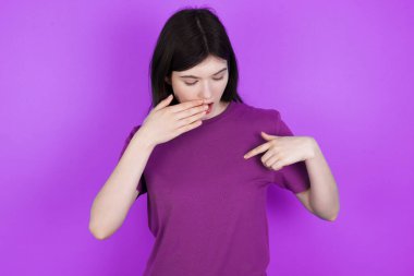 Şok olmuş genç esmer kadın şaşırtıcı bir şekilde aşağı bakıyor, işaret parmağıyla boş, korkmuş model.