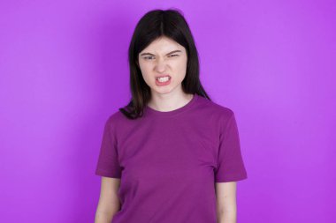 Genç esmer kadın dişlerini sıkar, tatminsizlikten kaşlarını çatar, görevleri yüzünden tedirgin olur..