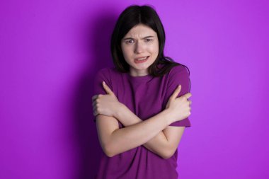 Umutsuz genç esmer kadın titriyor ve üşüyor, ısınmak için kendine sarılıyor ya da korkunç bir şey fark ediyor..