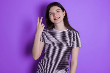 young brunette woman smiling and looking friendly, showing number two or second with hand forward, counting down