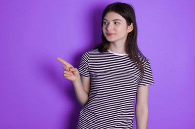 young brunette woman points at copy space and advertises something, advices best price.