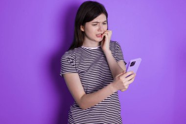 Oldukça korkmuş esmer bir kadının portresi. Akıllı telefonundan korkunç haberler okuduktan sonra tırnaklarını yiyerek sohbet ediyor..