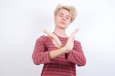 Genç sarışın adam Reddedilme ifadesi kollarını kavuşturarak negatif işaret yapıyor, kızgın yüz ifadesi.