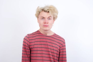 Memnun olmayan genç sarışın adam ağlayacak gibi bakıyor, hoşnutsuz ve mutsuz olduğundan hedeflere ulaşamıyor, hayal kırıklığına uğramış modelin sorunları var.