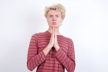 Olumlu genç sarışın adam mutlu bir şekilde gülümsüyor. Müdahaleciden hoş haberler aldığına seviniyor. Avuç içlerini bir arada tutuyor..