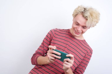 Hücrede el ele tutuşan genç sarışın adam video oyunları oynuyor ya da sohbet ediyor.