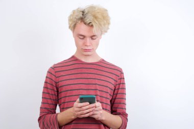 Heyecanlı genç sarışın göz kırpan ve göz göze gelen akıllı telefon kullanımı sosyal ağ haberlerini oku