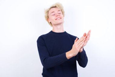 Genç sarışın adam alkışlıyor ve alkışlıyor mutlu ve neşeli, gülümseyen gururlu eller birlikte.